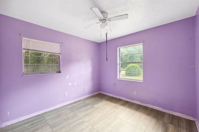 empty room with a textured ceiling and ceiling fan