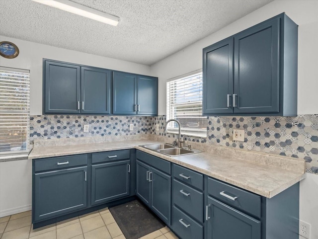 kitchen with blue cabinetry, sink, light tile patterned floors, and tasteful backsplash