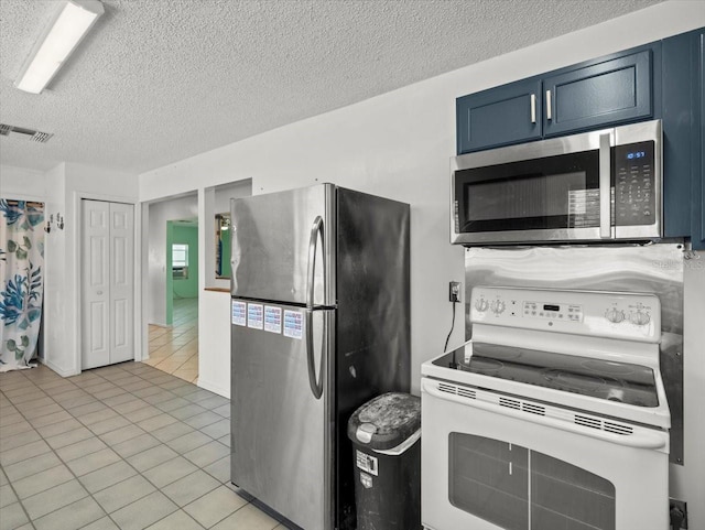 kitchen featuring stainless steel appliances, light tile patterned floors, blue cabinetry, and a textured ceiling