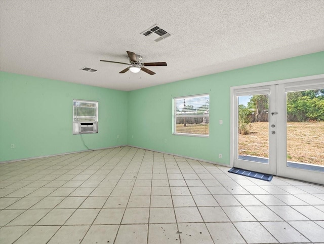 tiled empty room with ceiling fan, a textured ceiling, and french doors