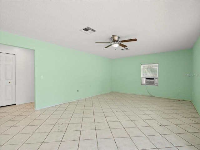 empty room with cooling unit, ceiling fan, light tile patterned floors, and a textured ceiling