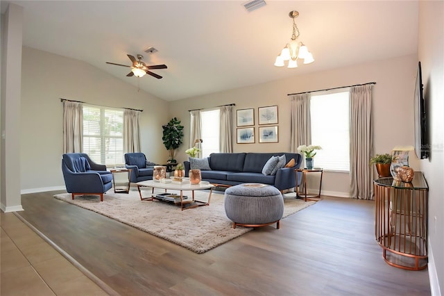 living room with ceiling fan with notable chandelier, vaulted ceiling, and hardwood / wood-style flooring