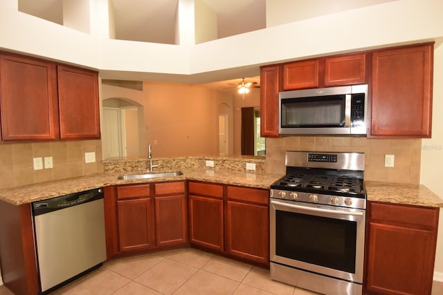 kitchen featuring sink, kitchen peninsula, appliances with stainless steel finishes, a high ceiling, and ceiling fan