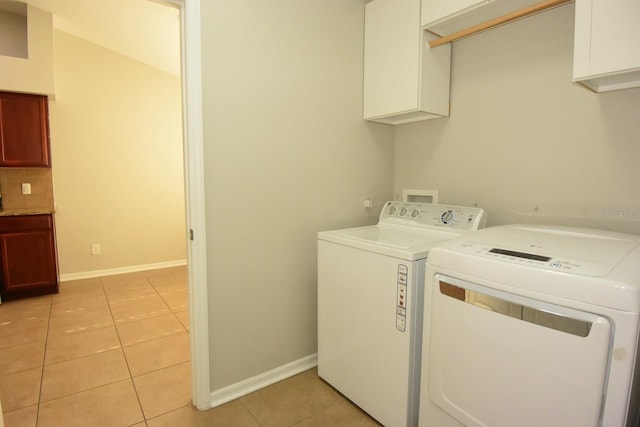 laundry room featuring cabinets, light tile patterned floors, and washing machine and dryer