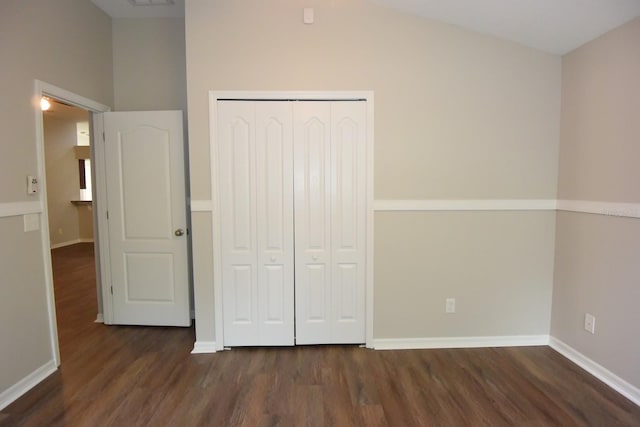 unfurnished bedroom with vaulted ceiling, dark wood-type flooring, and a closet