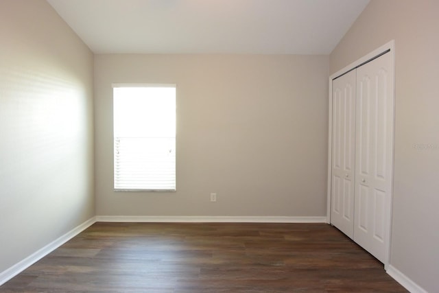 unfurnished bedroom with a closet and dark hardwood / wood-style flooring