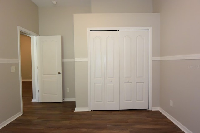 unfurnished bedroom featuring a closet and dark wood-type flooring