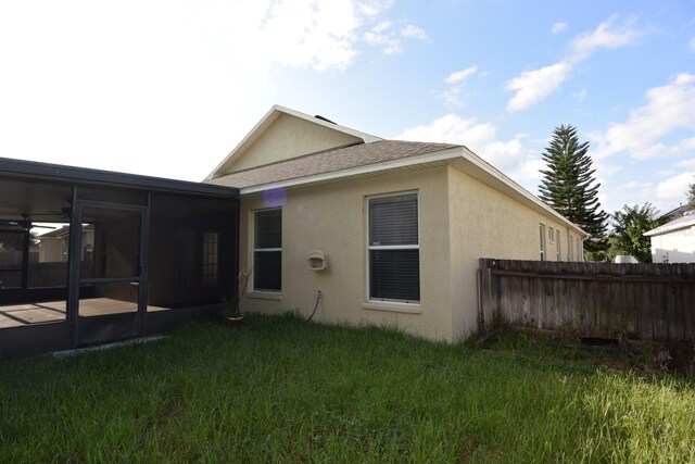 rear view of house with a sunroom and a lawn