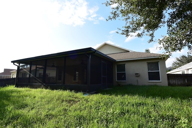 back of house featuring a sunroom and a lawn