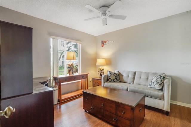 living room with light hardwood / wood-style flooring, ceiling fan, and a textured ceiling