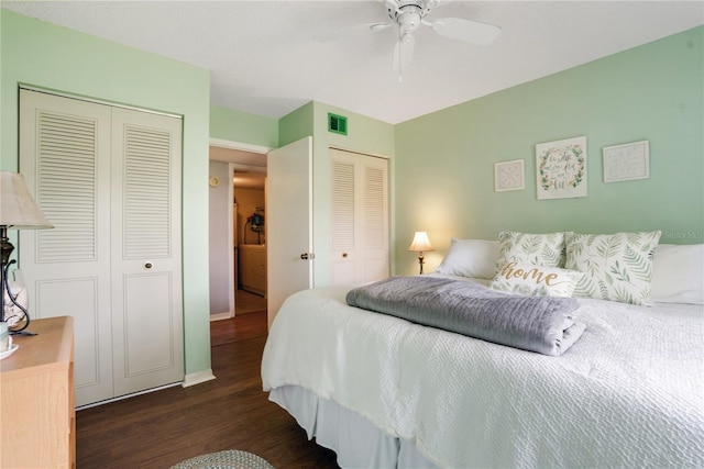 bedroom with dark hardwood / wood-style floors, ceiling fan, and multiple closets