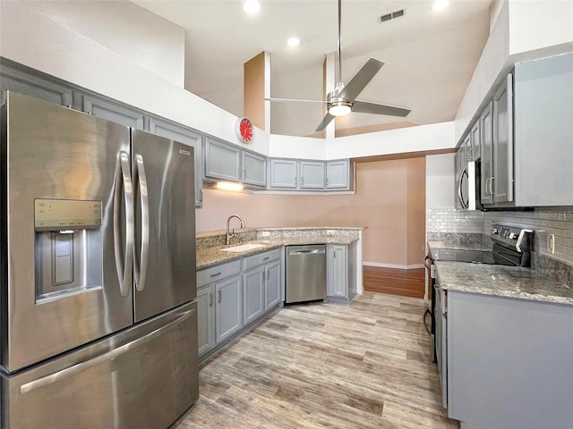 kitchen with decorative backsplash, high vaulted ceiling, light wood-type flooring, sink, and stainless steel appliances