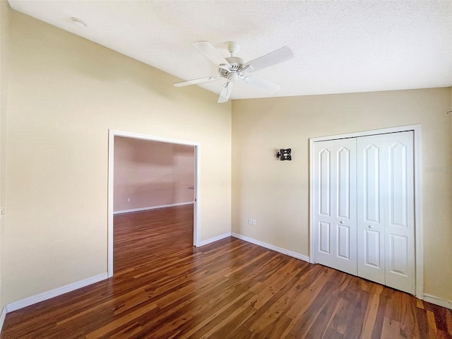 unfurnished bedroom featuring lofted ceiling, ceiling fan, a textured ceiling, dark wood-type flooring, and a closet