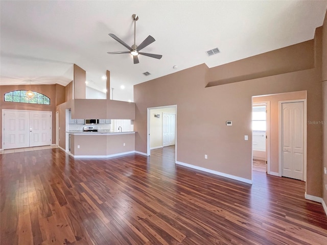 unfurnished living room with dark wood-type flooring, high vaulted ceiling, and ceiling fan