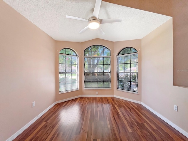 empty room featuring a textured ceiling, vaulted ceiling, dark hardwood / wood-style floors, and ceiling fan