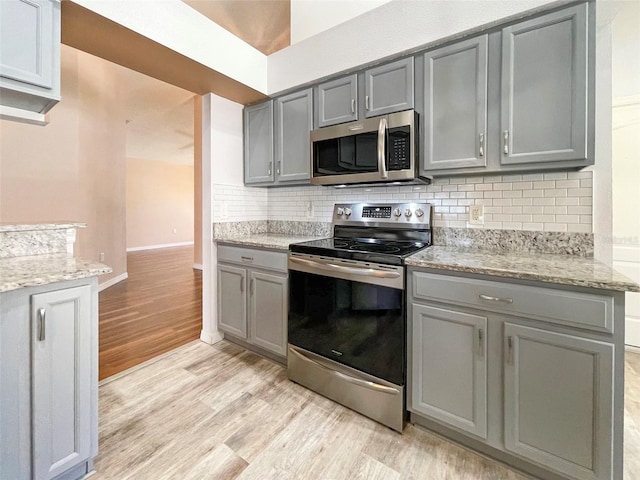 kitchen with stainless steel appliances, decorative backsplash, light wood-type flooring, and gray cabinets