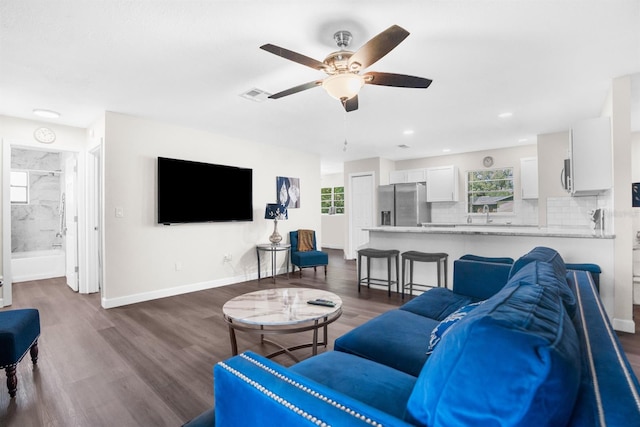 living room with ceiling fan, sink, and dark wood-type flooring