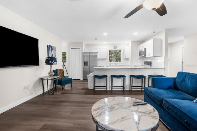 living room with ceiling fan and dark wood-type flooring