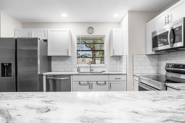 kitchen featuring light stone counters, white cabinets, appliances with stainless steel finishes, and sink