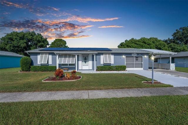 ranch-style house with solar panels, a lawn, and a carport