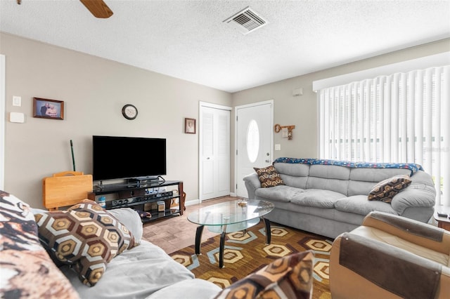 living room featuring ceiling fan, a textured ceiling, and hardwood / wood-style flooring