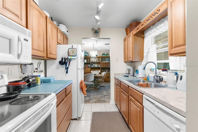 kitchen with light tile patterned floors, sink, white appliances, rail lighting, and an inviting chandelier