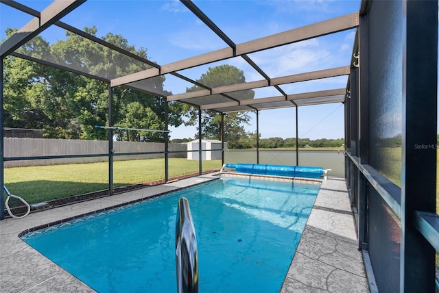 view of pool featuring a storage shed, glass enclosure, and a lawn