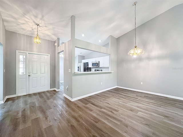 entryway with an inviting chandelier, hardwood / wood-style flooring, and high vaulted ceiling