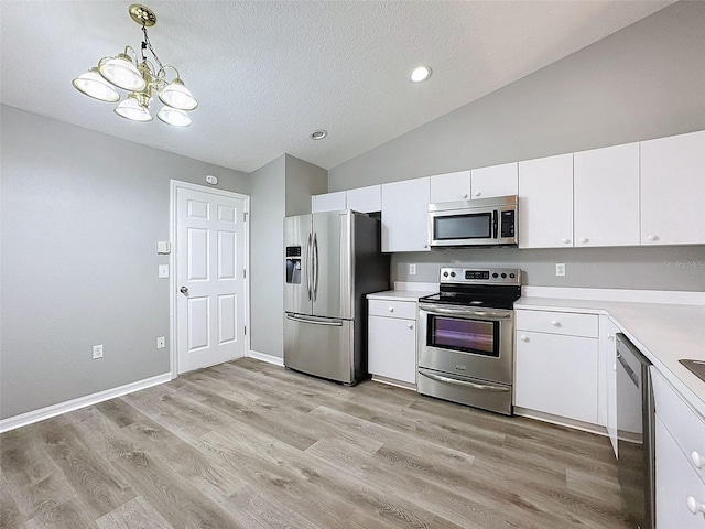 kitchen featuring appliances with stainless steel finishes, white cabinets, light wood-type flooring, an inviting chandelier, and decorative light fixtures