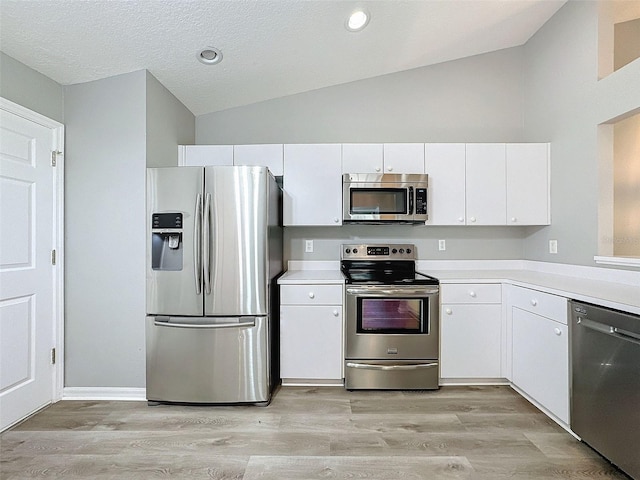 kitchen featuring light hardwood / wood-style floors, white cabinets, stainless steel appliances, a textured ceiling, and lofted ceiling