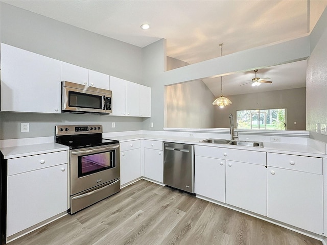 kitchen featuring white cabinets, pendant lighting, sink, light hardwood / wood-style flooring, and appliances with stainless steel finishes