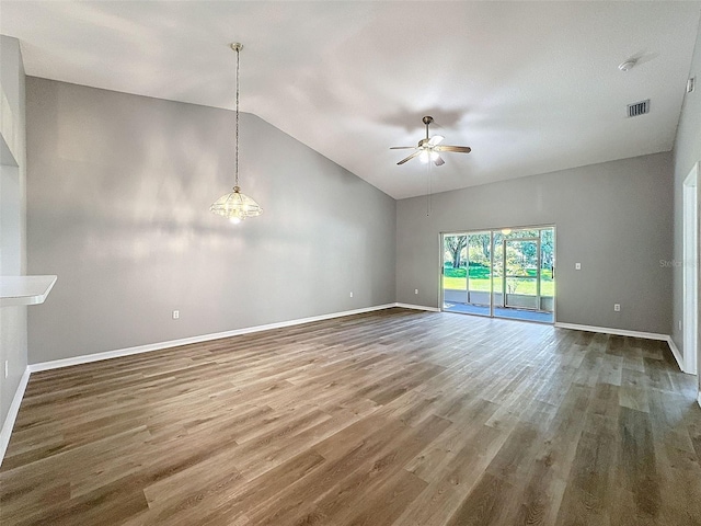 spare room featuring ceiling fan with notable chandelier, hardwood / wood-style floors, and high vaulted ceiling