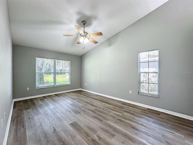 unfurnished room featuring vaulted ceiling, ceiling fan, hardwood / wood-style flooring, and plenty of natural light