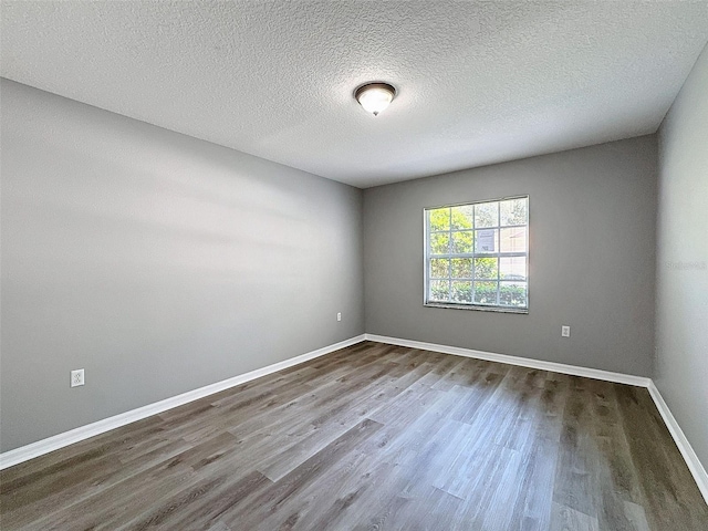 spare room with a textured ceiling and dark wood-type flooring