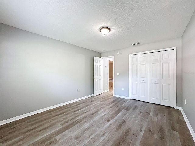 unfurnished bedroom featuring hardwood / wood-style flooring, a closet, and a textured ceiling