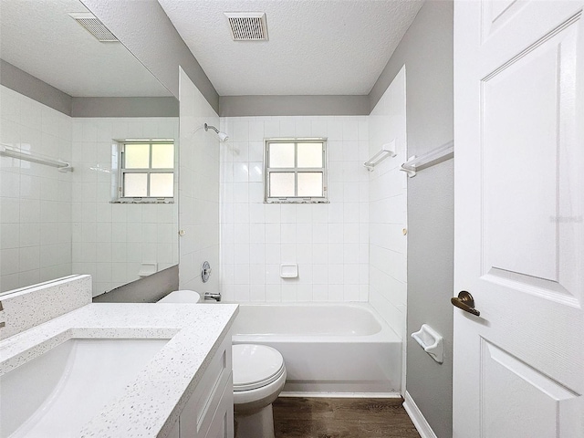 full bathroom with tiled shower / bath, hardwood / wood-style flooring, toilet, and a wealth of natural light