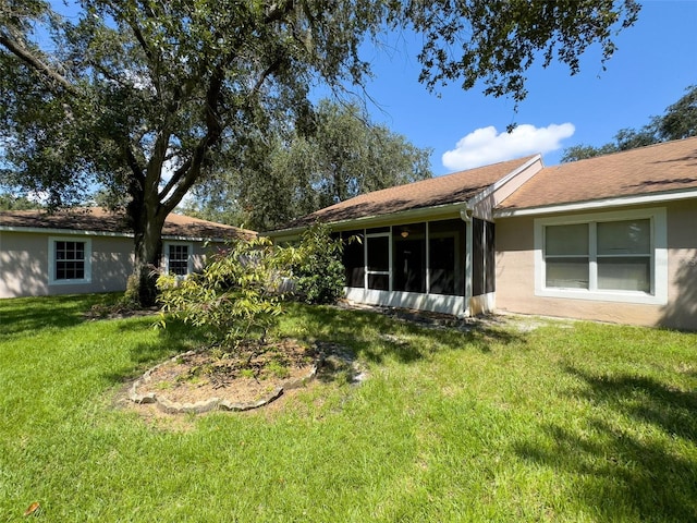 rear view of property featuring a sunroom and a yard