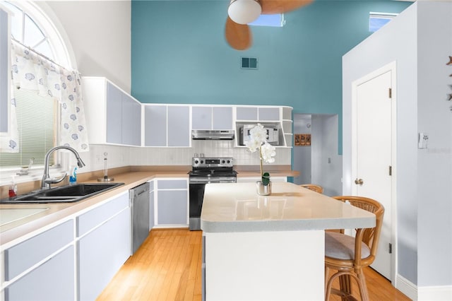 kitchen with a breakfast bar, a center island, sink, light hardwood / wood-style flooring, and stainless steel appliances