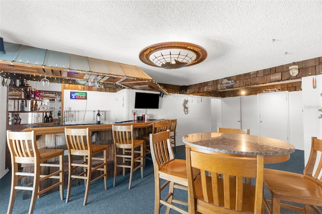 dining area with carpet, a textured ceiling, and bar