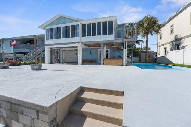 back of house featuring a sunroom, a patio, and a swimming pool with hot tub