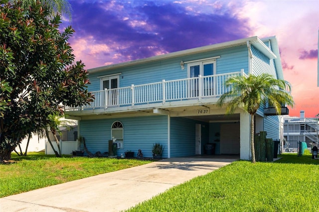 view of front facade with a balcony, a lawn, and a carport