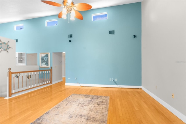 spare room featuring a towering ceiling, ceiling fan, and hardwood / wood-style flooring