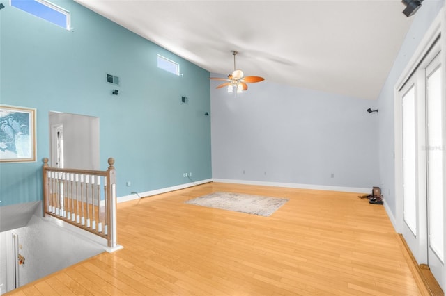 empty room featuring high vaulted ceiling, ceiling fan, light hardwood / wood-style flooring, and a healthy amount of sunlight