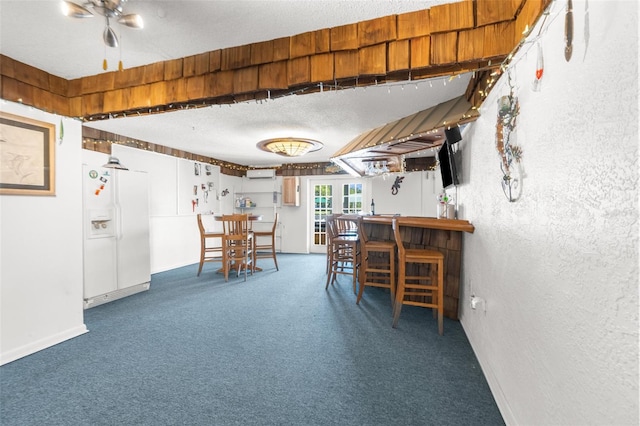 carpeted dining area featuring ceiling fan, a textured ceiling, and indoor bar