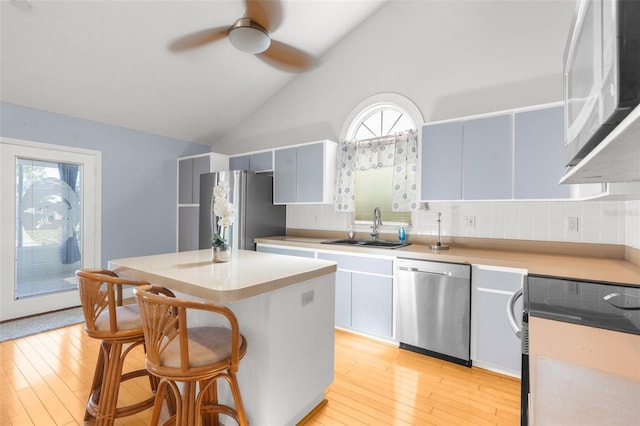 kitchen featuring light hardwood / wood-style flooring, appliances with stainless steel finishes, sink, and a center island