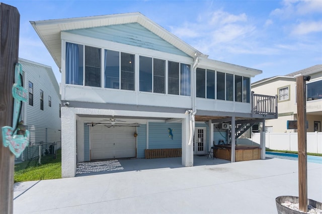 view of front of property featuring a garage, a sunroom, and a hot tub