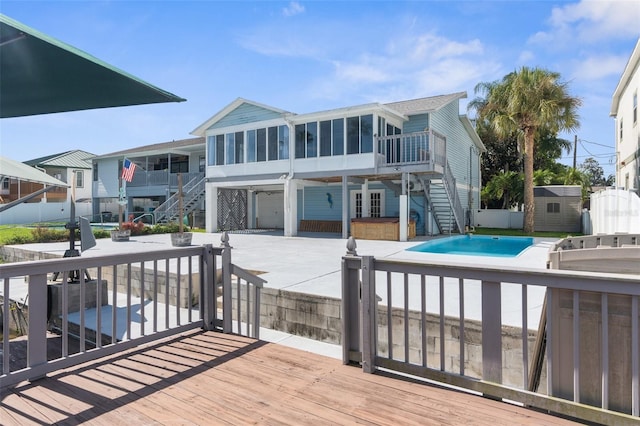 rear view of property featuring a patio, a swimming pool side deck, and a shed