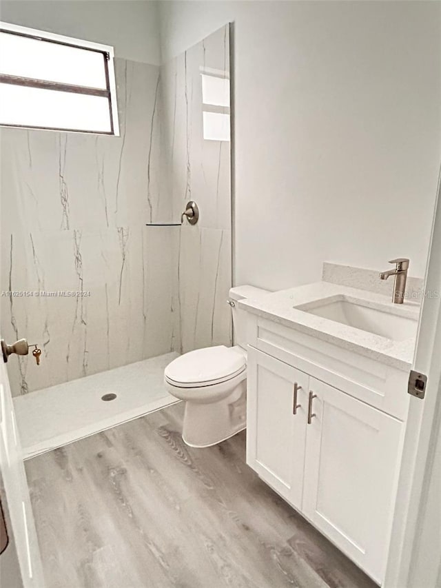 bathroom featuring tiled shower, hardwood / wood-style floors, vanity, and toilet