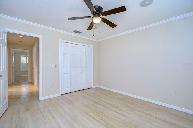 unfurnished bedroom with crown molding, light wood-type flooring, and a closet