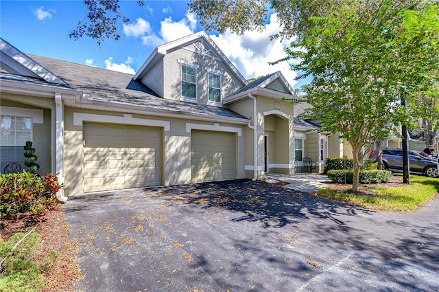 view of front of home featuring roof with shingles, aphalt driveway, and stucco siding